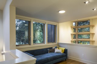 Overlooking the living room, a small loft area for watching television features a Movie Sofa by CB2 upholstered in Bayoux blue fabric. By building vertically, Stillwater was able to spare the home’s wooded surroundings. 