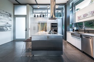 From the Ashes - Photo 3 of 4 - The house is laid out on three levels, with the main entrance leading to the top-floor kitchen, which features concrete floors, quartz counters, a refrigerator and wall oven by Electrolux, and a stainless-steel apron-front sink from Kraus. Image by Hector Magnus.