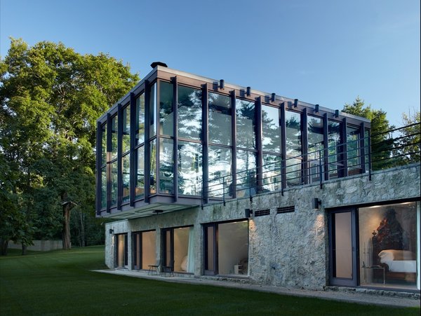 Shown here is a view of the stone and concrete structure that supports the cantilevered glass pavilion. The bottom section holds four bedrooms, bathrooms, and a sitting room. The glass and wood pavilion on top houses a combined living, dining, and kitchen space—all which is surrounded by 15-foot-tall windows. Photo 3 of Wiley House modern home
