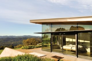 Contrasting expanses of glass and rammed earth wrap Bill Gawthrop and Diane Taylor’s home in Yorkville, California. The couple’s bedroom is located at one end of the house and their offices are at the other, with an open-plan kitchen, living room, and dining area in between. The bed frame is Gawthrop’s own design. 