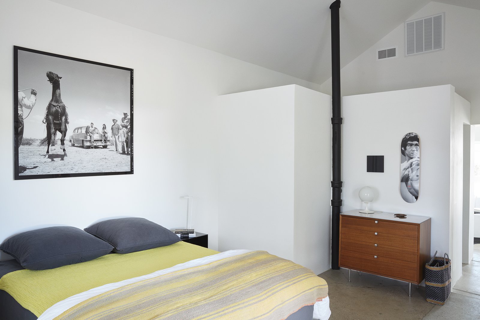The ceiling is 15 feet high in the bedroom, where a photograph from the set of the movie Giant, which was filmed in Marfa, complements <br>a chartreuse throw from El Cosmico and a Bruce Lee Supreme skate deck from Exhibitions 2d.