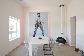 "Everything out here has been something else," designer Barbara Hill says of Marfa, Texas. It’s certainly true of her casita, which was formerly a grocery store: The 1,200-square-foot home is filled with reworked pieces, including <br>the Elvis artwork she embellished with pink lights fabricated by the Neon Gallery in Houston and the <br>refurbished Bertoia chairs from <br>Cast + Crew. The minimal color <br>palette is echoed in the freestanding <br>Malm fireplace and the concrete floor sculptures by William Vizcarra from Wrong Marfa. 