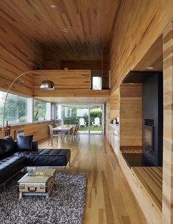 The interior of locally milled poplar contrasts with the home’s metal exterior. Thanks to the six-degree pitch of the site, the dining area leads directly to the yard, while the living room ends with a balcony that’s high above the ground.