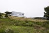 Modern home with side yard, exterior, slope, field, metal siding material, and house. Imagined as a jewel box on a hill, Sliding House takes the place of a barn that once stood on this Nova Scotia site. Its form follows the slope of the land, while the windows are parallel with the horizon, setting up a tension between a plumb interior and a slanted exterior. The tilt of the structure isn’t just a visual trick—it also helps the roof to drain. When the distinctive windows are lit from within, the house serves as a beacon for local sailors. Photo of Sliding House