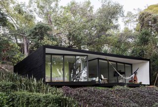 Constructed of steel, glass, and concrete, the exterior is clad in a dramatic black shade with a floor-to-ceiling glass facade—offering views of the valley below from the outdoor lounge area and pool. 