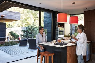 Greener Grass - Photo 1 of 14 - Ian Jones and Debra Peat enjoy fresh fruit grown in the backyard of their Seattle, Washington, home. Relocating from a rural community, the couple brought their passion for gardening to their new urban setting. Sliding doors from Quantum wrap around the kitchen and open to an expansive courtyard and deck, which is furnished with armchairs from Crate and Barrel. Smith pendants from Resolute hang above the PentalQuartz and marble island; the oven and dishwasher are from Miele.