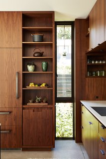 Greener Grass - Photo 3 of 14 - In the kitchen, an elongated window breaks the custom walnut cabinetry by Contour Woodworks. 