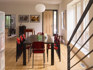 The first floor’s open plan combines kitchen, dining, and living areas; <br>rift-sawn white oak planks line the floors throughout. "It’s a tremendous enhancement of our life together," Louis says of the layout. Standard chairs by Jean Prouvé for Vitra surround the beeswax-coated steel dining table. 