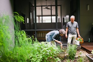Marsha and Louis collect herbs <br>in a garden by their screened porch (above). The home’s exterior cypress cladding is finished with Sikkens ProLuxe Cetol stain in Teak.