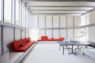 Across the Ocean - Photo 2 of 10 - The main living area, on the home’s second floor, was designed with flexibility in mind; its centerpiece is a ping-pong table from Joola. Anton and Débora "hacked" several Copa convertible sofas from Serta, removing the legs so they could place the seats directly onto the elevated platform that lines the walls. They also altered Lersta floor lamps from IKEA and wall-mounted them as sconces.