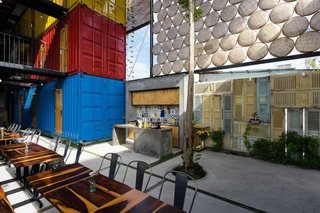 Stacked shipping containers—painted red, blue, and yellow to distinguish the different room types—are arranged around a large socializing area for guests. 