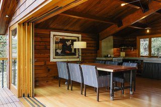 On the main floor, custom sliders by Oakridge Windows & Doors open to a table and chairs designed by Paquette and built by Conrad Contracting. The wood paneling on the walls was salvaged from the original structure and resawn; each piece was scuffed with fine sandpaper and coated with Projectol. 
