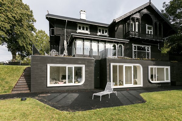 The design team lowered the cellar floor by a foot and extended a rear-facade addition toward the lake. “I am all for an architecture for its time—this house had a strong personality,” Jens says. “The overscale windows create a tension, a dialogue . . . it’s a new element, but one that celebrates the original idea.” Photo 4 of Skibsted Residence modern home