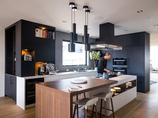 Domino Effect: How a Bedroom Refresh Jump-Started a Whole-House Remodel For a Tech Exec - Photo 9 of 14 - The black steel A110 pendants by Alvar Aalto match the Poliform ventilation hood and ebonized white oak cabinets by Leicht Haus. LED lighting is integrated into the island shelving. The drawers underneath are handleless and open electronically by touch using a servo drive. 