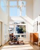 Tom and Kate own the top two floors of the building. On the lower level, in the double-height foyer, Milo Baughman’s Recliner 74 is positioned beneath Rudi Double Loop pendants by Lukas Peet for Roll & Hill. The floor lamp is a custom piece that De Angelis Designs adapted from a vintage salon hood dryer. Photo 3 of Conrad Residence modern home
