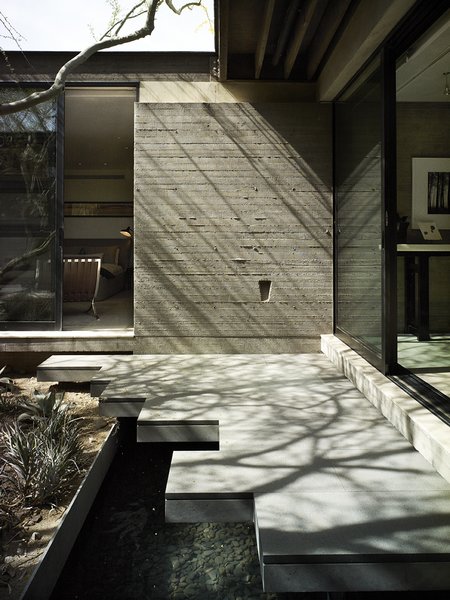 Modern home with hardscapes, shrubs, stone patio, porch, deck, concrete counter, ceiling lighting, and outdoor. Board-formed concrete walls create the core of the house and establish its organic feel. "There’s really no other cast-in-place concrete on the street," says Sarah, "but you don’t even see it until you’ve made it through the front courtyard." There, beneath a deep overhang, the couple designed a jagged pathway cantilevered over a water inside and reflections of light into the sitting area. Photo 6 of Wessel Residence