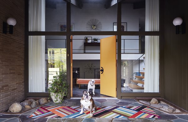 Modern home with outdoor. By scouring shops, sales, and auctions, George Marrone amassed a giant trove of postwar furniture. He and his partner, Michael Nocera, applied that same work ethic to a 1959 home in Wilmington, Delaware, which they patched up over two years. The couple’s bulldogs stand guard at the flagstone entrance. The door, still with its Space Age knobs, is painted Flaming Torch by Behr. The brass wallhanging above the landing is by C. Jeré. Photo 2 of The Marrone/Nocera Residence