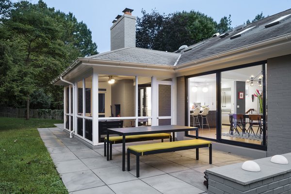 Modern home with outdoor, back yard, stone patio, porch, deck, grass, and large patio, porch, deck. “This is not a custom home—it’s the case of a builder who put something up in D.C. catering to a more traditional market,” explains Balodemas. “He framed the ceilings down to make them symmetrical. It would’ve been weird at that time to have the rooms oddly shaped. People were way too timid back then.” The rear terrace features new pavers from Pennsylvania Blue Slate and Crate and Barrel seating. Photo 7 of The Bruning/Owen Residence