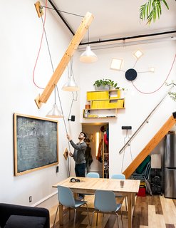 Devising Clever Solutions For a Small San Francisco Loft - Photo 2 of 10 - Max devised a movable plywood beam that holds a trio of pendant lamps to swing down as needed. A wood piece covered in chalkboard paint hides the electrical panel. "Slate was too expensive," he says. 