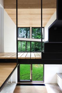 The second floor is a master bedroom, bathroom, and mechanical room, along with an open volume that fills the house with light from the Alumilex doors and windows. The paint is Distant Gray by Benjamin Moore. 