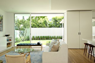 Two Grad-School Friends Apply Their Know-How to a Manhattan Beach Bungalow - Photo 2 of 9 - The living room is defined by large glass sliders by Fleetwood that open up to the backyard, allowing light to flood the downstairs space. The room features a Crosby sofa by West Elm, CH25 lounge chairs by Hans J. Wegner for Carl Hansen & Søn, and an OW 150 daybed by Ole Wanscher. 