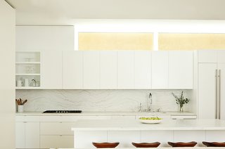 Two Grad-School Friends Apply Their Know-How to a Manhattan Beach Bungalow - Photo 4 of 9 - The kitchen is defined by Olympian White Danby marble counters and a backsplash by Stone Source. The Tractor stools are by Craig Bassam for BassamFellows. 