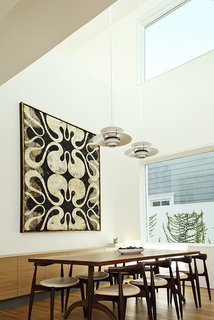 Two Grad-School Friends Apply Their Know-How to a Manhattan Beach Bungalow - Photo 5 of 9 - The home’s open floor plan combines the dining and living areas into a shared space. The dining table is a custom walnut plank top with a base by Organic Modernism. It is surrounded by CH20 Elbow chairs by Hans J. Wegner for Carl Hansen & Søn.