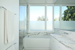 Two Grad-School Friends Apply Their Know-How to a Manhattan Beach Bungalow - Photo 9 of 9 - The master bathroom is complete with a honed statuary F Italian white marble slab countertop, shower wall, and floor. The honed white Corian tub is by Hydro Systems. 