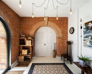 A Refurbished Victorian-Era Brick Tower in Hampshire - Photo 2 of 9 - Each floor of the tower is about 160 square feet. Prior to the formal renovation, Sheryl added mosaic tile from Fired Earth in the entrance hall. The hanging lights are by Industville and the high-back chair is by Nigel Griffiths. 