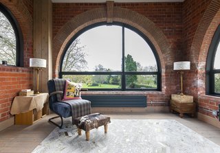 A Refurbished Victorian-Era Brick Tower in Hampshire - Photo 5 of 9 - The facade is punctuated by windows of various shapes, including half-moons by Crittall. The armchair and chevron rug are from Graham & Green. 