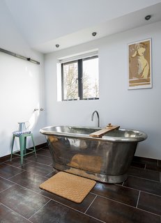 A Refurbished Victorian-Era Brick Tower in Hampshire - Photo 7 of 9 - A freestanding copper tub, also by William Holland, sits exposed in a corner of the bathroom. The matching tile for the vanity and floor is by Marco Polo.