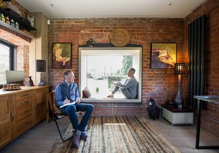 A Refurbished Victorian-Era Brick Tower in Hampshire - Photo 8 of 9 - A lens-like window, whose steel frame juts out toward the courtyard, has a built-in beech plywood seat for admiring New Forest National Park. The chair is vintage.