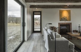 An Artist and Farmer Work With a Toronto-Based Studio to Build a Barn-Inspired Home - Photo 3 of 11 - "We were researching places where we could get fake old beams, but at the last minute, the contractor found some from a barn that was coming down," recalls architect Vivian Lee. In the living area, Blanche sofas by EQ3 are paired with Library task floor lamps from Restoration Hardware. The painting is by Brian Burke. 