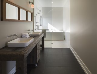 An Artist and Farmer Work With a Toronto-Based Studio to Build a Barn-Inspired Home - Photo 8 of 11 - The master bathroom features sinks and fixtures by Kohler. The tub is by Aktuell. 
