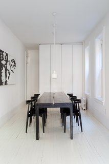 A Pair of Designers Renovate Their Brooklyn Brownstone With a Bright Monochromatic Palette - Photo 10 of 12 - Elbow chairs by Hans J. Wegner for Carl Hansen & Søn surround a table of the couple's own design. By removing walls in this space, extra storage was possible. The trio of A330S pendants are by Alvar Aalto for Artek. The painting, The Look, is by Ed Parker. 
