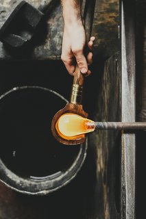 Master Glassmaker Simon Pearce's Sustainable Factory in Vermont - Photo 8 of 16 - Blocking Next, the honey-like material is blocked, or centered and cooled, using a cherry wood tool kept wet in a pail of water. The process keeps the glass from becoming too "wobbly."