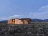 Modern home with Desert, Shrubs, Exterior, Stucco Siding Material, House, and Wood Siding Material. On a five-acre property outside Taos, New Mexico, designer Molly Bell worked closely with her father, builder Ed Bell, to create a new residence for owner Lois Rodin. “Lois requested that it appear as a grouping of individual masses, so that it read more like a cluster than a solitary shape,” Molly says. “I hope it shows that it’s OK to do something modern in such a traditional environment, and not to be afraid of it.” Photo 2 of Rodin Residence