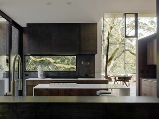 Nature Drove the Design of This Sculptural, Cor-Ten Steel House in Northern California - Photo 3 of 13 - In the kitchen, bar stools by Living Divani pull up to an island with Bretonstone countertops; the faucet is by Blanco. 