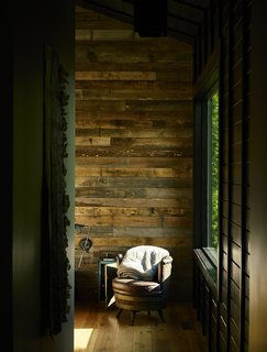 A Rustic-Modern Cabin Inspired by Japanese Bungalows and Shou Sugi Ban - Photo 4 of 12 - In each room, a single wall was clad in reclaimed poplar. An antique barrel chair sits in the master bedroom. 