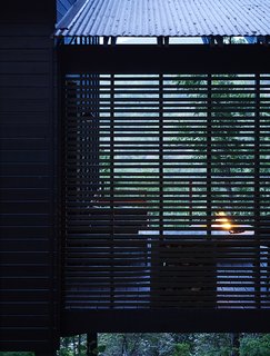 A Rustic-Modern Cabin Inspired by Japanese Bungalows and Shou Sugi Ban - Photo 6 of 12 - Pine slats, which were intentionally spaced unevenly, partially enclose the side deck. Outdoor areas add nearly 300 square feet to the cabin, whose interior measures about 1,000 square feet. 