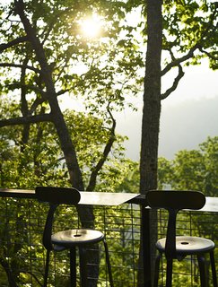 A Rustic-Modern Cabin Inspired by Japanese Bungalows and Shou Sugi Ban - Photo 11 of 12 - For dining outdoors, Restoration Hardware stools are paired with movable steel trays. A table that nests on top of the kitchen counter can also be wheeled outside. 