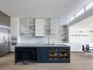 A Historic Victorian in San Francisco Is Meticulously Transformed Into a Modern Family Home - Photo 16 of 26 - The home’s kitchen features dual Miele ovens, a Thermador refrigerator and freezer, and a Thermador induction cooktop. A feature wall clad in natural Carrara marble sits behind sliding cabinet uppers. Heron counter stools by Paola Lenti in ‘verde scuro’ coordinate with custom cabinet fronts, which are accented with Spinneybeck leather pulls.