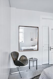 A Careful Renovation of a 19th-Century Flat in Gothenburg Brings it Back to Life - Photo 10 of 11 - In the bedroom, a weathered Swan chair by Arne Jacobsen is next to a table designed by Vipp. 