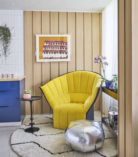 An Interior Designer Helps His Mother Turn Her 1960s Chicago Apartment Into a Colorful Haven - Photo 2 of 8 - Near the kitchen, a Moel chair by Inga Sempé for Ligne Roset joins a bar trolley, side table, and pouf from Crate and Barrel. A Yannis Gaitis lithograph hangs on a wall of white oak plywood. Architect Mike Shively came up with the vertical strips to add texture.