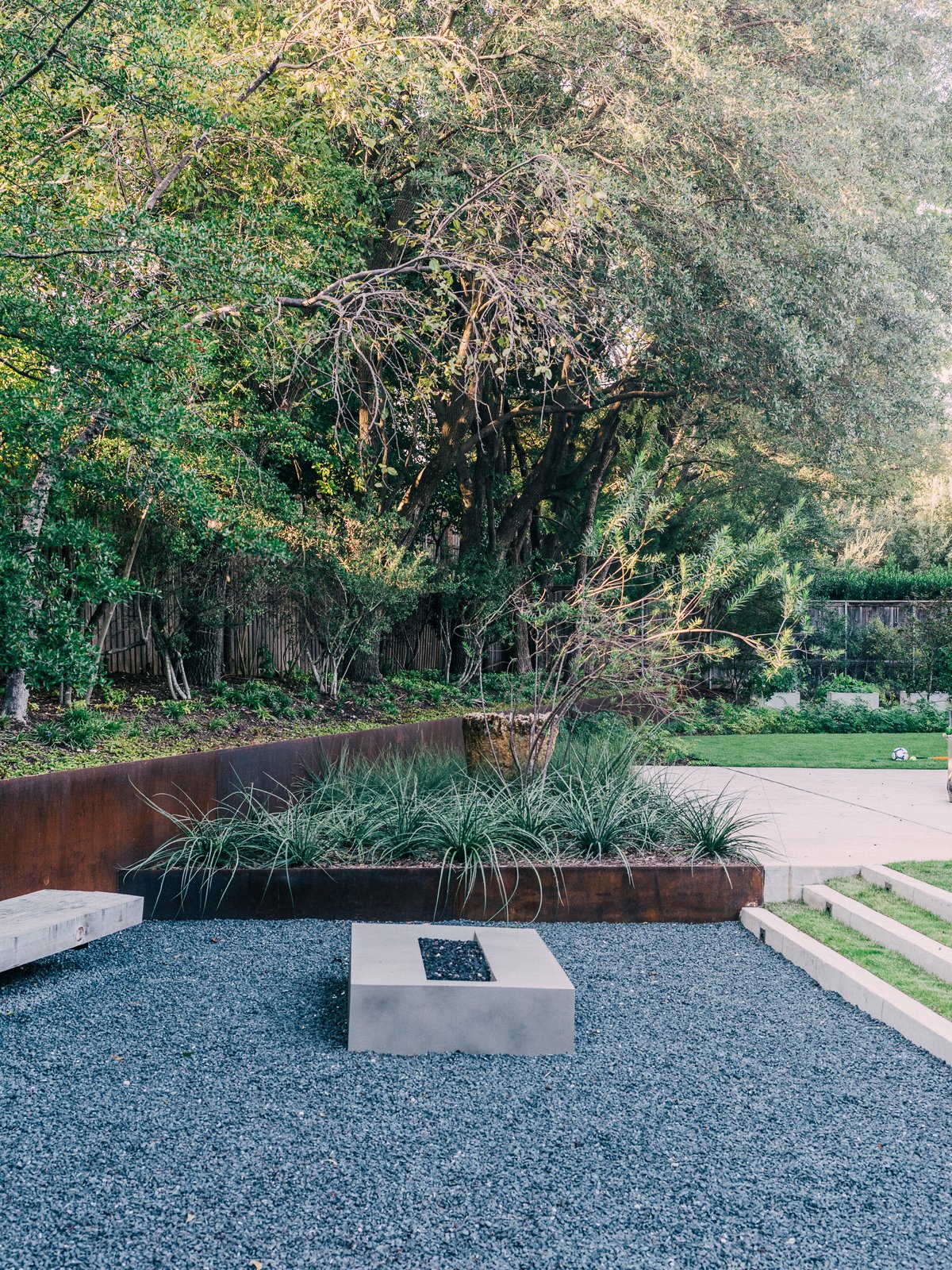 Behind her is the greenhouse, where Lynn starts vegetables like lettuce, Swiss chard, and tomatoes. Landscape architect David Hocker defined the sunken fire pit area with Cor-Ten steel.