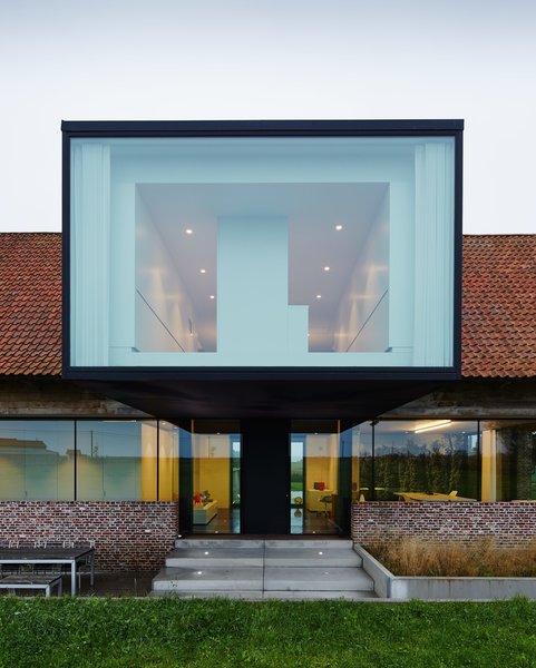 “To be able to respect the ‘massiveness’ of the roof, making bigger windows would be wrong, because we would lose the character of the farm,” Wynants explains. “Therefore, I was looking for other ways to collect light. At this spot you had the big barn doors at both sides: This is the economical axis of the farm. This I kept, as my own design office is right under this volume. It keeps the sun out, so I have a splendid view when I’m working—I never need sun shades.” Photo 3 of Wynant House modern home
