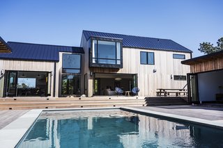 You Won't Lose Your Wi-Fi Connection at This Hamptons Retreat - Photo 1 of 6 - Bi-fold doors connect the main residence to the backyard, which features a large swimming pool, a 200-square-foot pool house, and an outdoor kitchen.