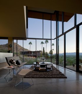 Taking it to the Desert With Dwell Home Tours - Photo 2 of 12 - With floors made of cork and concrete, the house is surrounded by substantial panels of translucent glass. The double-height living room acts as a collective open space that looks out to the dramatic views of the desert. 