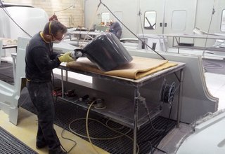 Bringing Back a Forgotten Material - Photo 6 of 7 - The pieces are designed in Italy and manufactured in Portugal, where De La Espada’s workshop is known for their high-quality woodworking skills. Shown here is a craftsman at work, carefully sanding the fiberglass shells that are fabricated through multiple steps—from forming a mold to the final piecing together. 
