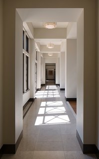 This House Takes on Gusty Winds and an Earthquake Fault - Photo 5 of 9 - Garcia placed Marvin windows all along an extensive corridor. The windows let natural light pour in while allowing the x-shaped wood beams from the exterior overhangs to reflect their shadows along the limestone flooring. 
